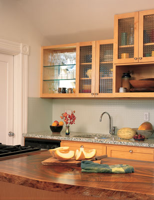 
Kitchen counters were crafted from recycled glass and wood sliced from a storm-fallen bay laurel. A window doubles as a shelf, filling wine glasses with light.
